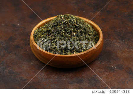 Green tea with herbs in wooden bowl on a wooden board Green tea with herbs in wooden bowl on a wooden board 130344518
