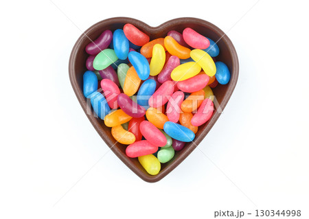 multi-colored sweet candies in heart shaped bowl on white background, top view. Space for text multi-colored sweet candies in heart shaped bowl on white background, top view. Space for text 130344998