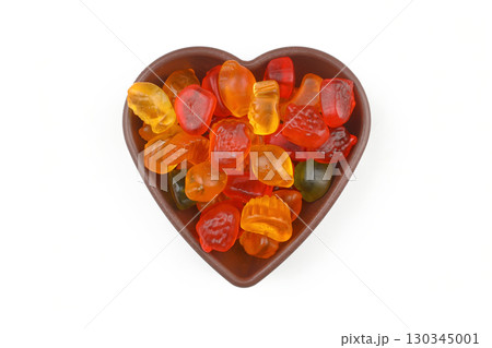 multi-colored sweet candies in heart shaped bowl on white background, top view. Space for text 130345001