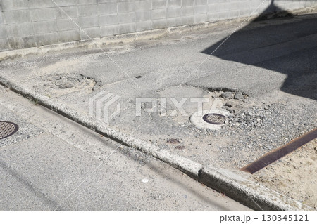 荒れた路面と道路の凹み。不十分なメンテナンスの生活道路。 130345121