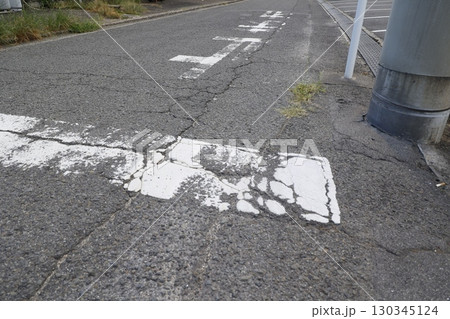 荒れた路面と道路の亀裂。一時停止線と止まれ標示。 130345124