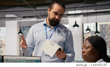 Team of technicians brainstorming solar powered device design using alternative energy technology. RD department office coworkers creating eco friendly solar gadgets prototypes, camera B 130345197
