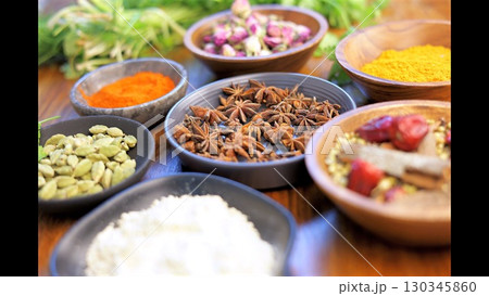 Rustic wooden surface displaying colorful spices and herbs in small ceramic bowls, representing culinary diversity and aromatic potential Rustic wooden surface displaying colorful spices and herbs in small ceramic bowls, representing culinary diversity and aromatic potential 130345860