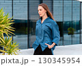 Confident woman in blue shirt walking outdoors 130345954