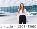 Confident businesswoman standing outside modern 130345960