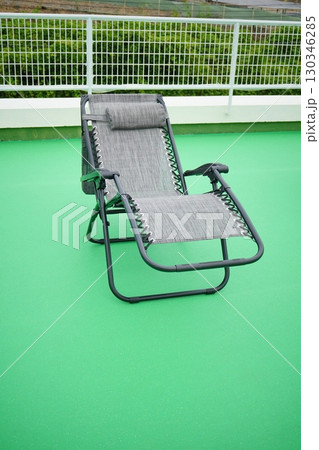 屋外に置かれたグレーのリクライニングチェアと緑の床の風景 130346285