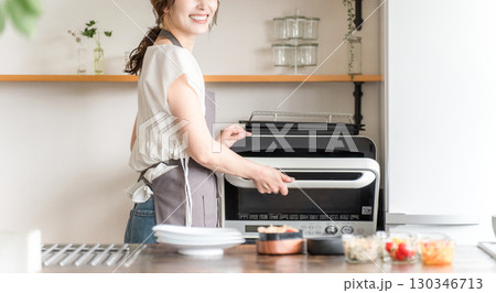 キッチンで電子レンジを使う女性(顔なし) キッチンで電子レンジを使う女性(顔なし) 130346713