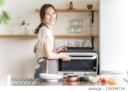 キッチンで電子レンジを使う女性(笑顔) キッチンで電子レンジを使う女性(笑顔) 130346714