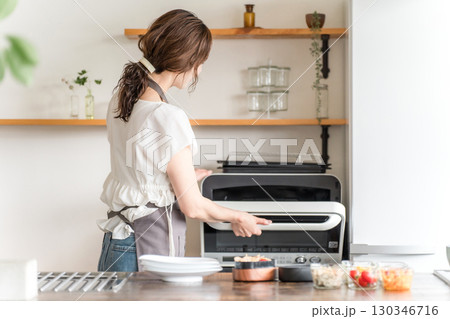 キッチンでキッチンで電子レンジを使う女性 キッチンでキッチンで電子レンジを使う女性 130346716