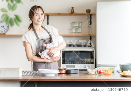 キッチンで赤ちゃんを抱っこする若いアジア人女性 130346789