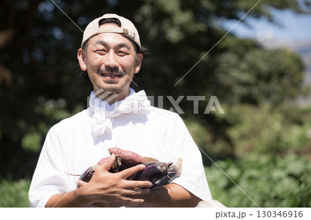 畑で野菜を収穫する男性 農家や農業で働くする人のイメージ カメラ目線の笑顔のクローズアップ 畑で野菜を収穫する男性 農家や農業で働くする人のイメージ カメラ目線の笑顔のクローズアップ 130346916