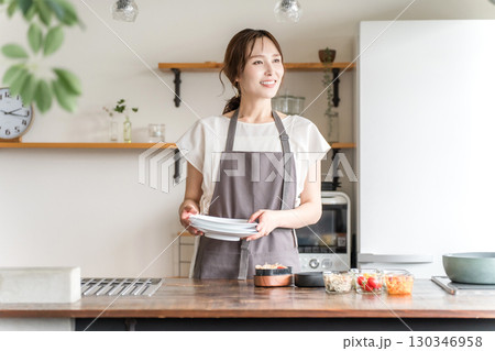 キッチンで家事をするエプロン姿の若いアジア人女性 130346958