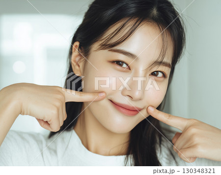 頬を指さす笑顔の日本人美容モデルが魅せるスキンケアルーティン（美容 広告 SNS） 130348321