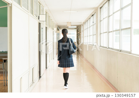 学校の廊下を歩く制服姿の小学生,中学生,高校生の女子生徒の後ろ姿 130349157