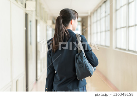 学校の廊下を歩く制服姿の小学生,中学生,高校生の女子生徒の後ろ姿 130349159