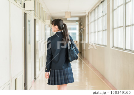 学校の廊下を歩く制服姿の小学生,中学生,高校生の女子生徒の後ろ姿 130349160