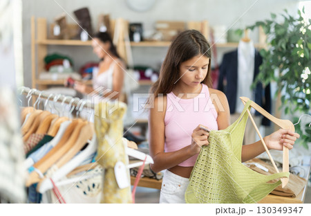Teenage girl choosing something for summer in clothing store Teenage girl choosing something for summer in clothing store 130349347