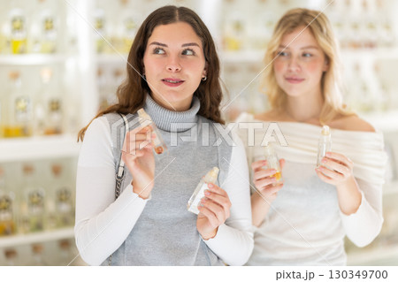 Two girlfriends choose aromatic perfumes together in perfume shop Two girlfriends choose aromatic perfumes together in perfume shop 130349700