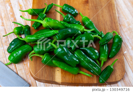 Pile of fresh green padron peppers on wooden background Pile of fresh green padron peppers on wooden background 130349716