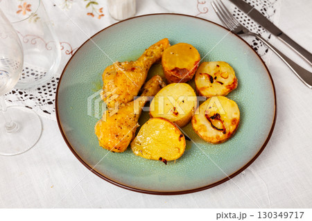 Two roasted chicken legs with skinned baked potatoes Two roasted chicken legs with skinned baked potatoes 130349717