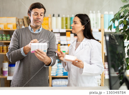 Man chooses packages with pills against the background of pharmacist Man chooses packages with pills against the background of pharmacist 130349784