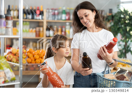 Child girl with mother choose consider juice Child girl with mother choose consider juice 130349814