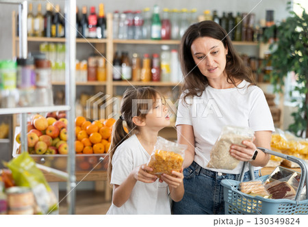 Child girl with mother choose consider cornflakes and oat flakes Child girl with mother choose consider cornflakes and oat flakes 130349824