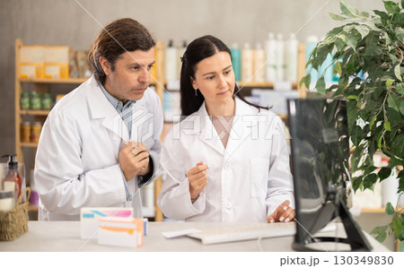 Two pharmacists searching for information on the internet together in pharmacy interior Two pharmacists searching for information on the internet together in pharmacy interior 130349830