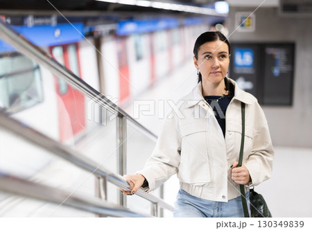 Woman metro passenger climbs stairs, enters underground public transport station Woman metro passenger climbs stairs, enters underground public transport station 130349839