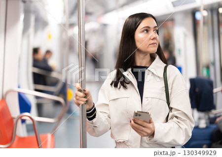 Woman with phone stand in metro carriage. Woman with phone stand in metro carriage. 130349929