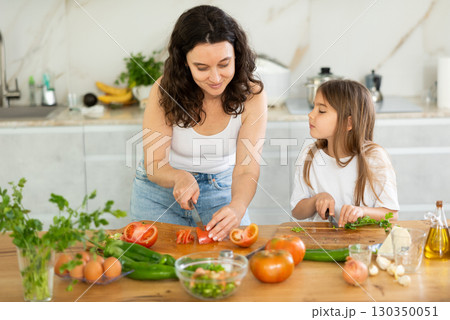 Mother and daughter cutting salad Mother and daughter cutting salad 130350051
