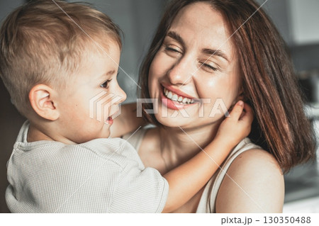 Happy cheerful mother holding her child in arms, enjoying family time and expressing love and joy. Happy cheerful mother holding her child in arms, enjoying family time and expressing love and joy. 130350488