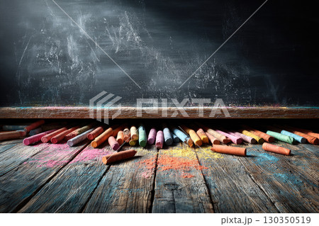 Colorful chalks on wooden floor with blackboard background Colorful chalks on wooden floor with blackboard background 130350519