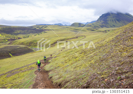 Cyclists exploring the vibrant landscapes of Iceland's rugged terrain in the highlands Cyclists exploring the vibrant landscapes of Iceland's rugged terrain in the highlands 130351415