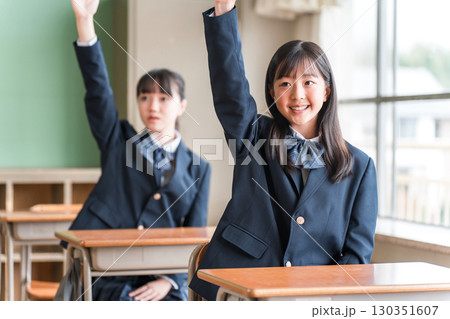 学校の教室で授業中に挙手する積極的な制服姿の小学生・中学生・高校生・女子高生（友達） 130351607