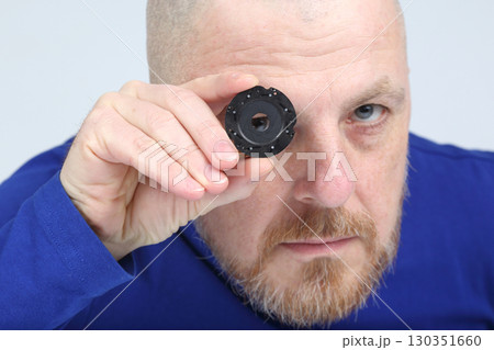 Expert examines a small black component while showcasing intricate design and detail Expert examines a small black component while showcasing intricate design and detail 130351660