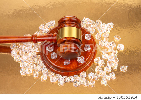 Legal gavel surrounded by sparkling gems on a reflective golden surface 130351914