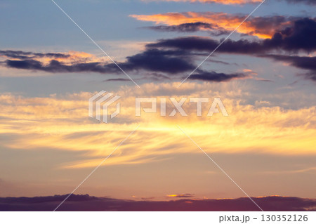 Colorful sunset sky over horizon filled with vibrant clouds during evening twilight hours 130352126