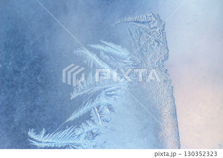 Frost patterns create intricate designs on a glass surface during a cold winter morning Frost patterns create intricate designs on a glass surface during a cold winter morning 130352323