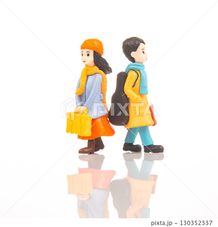 Miniature figures walk in opposite directions with luggage and musical instrument 130352337