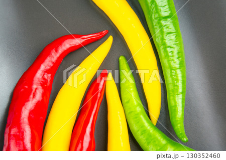 Colorful assortment of chili peppers arranged on a black surface in a vibrant display Colorful assortment of chili peppers arranged on a black surface in a vibrant display 130352460