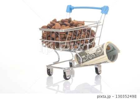 Shopping cart filled with coffee beans and a rolled dollar bill on a white background 130352498