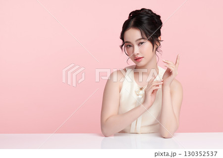 A beautiful young Asian woman with clean, fresh skin against a pink background. Skincare, facial treatment, cosmetology, beauty, and spa. An elegant portrait of an Asian woman. A beautiful young Asian woman with clean, fresh skin against a pink background. Skincare, facial treatment, cosmetology, beauty, and spa. An elegant portrait of an Asian woman. 130352537