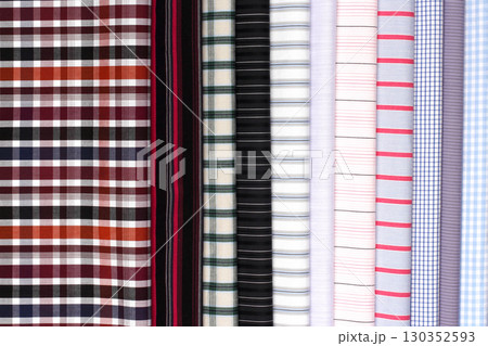Vibrant collection of various plaid and striped fabrics displayed in a bright setting 130352593