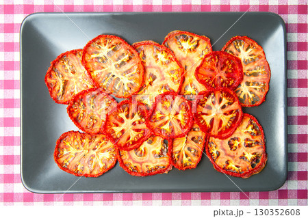 Dehydrated tomato slices arranged on a black platter on a red and white checkered tablecloth Dehydrated tomato slices arranged on a black platter on a red and white checkered tablecloth 130352608