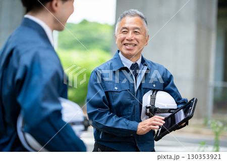 建設現場で会話する若手とベテラン技術者 130353921