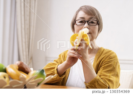 ダイニングでバナナを剥いて食べるシニア女性 ダイニングでバナナを剥いて食べるシニア女性 130354369