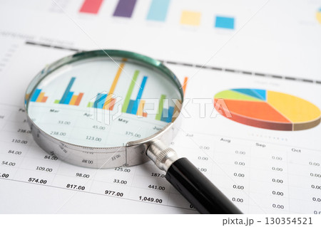 Magnifying glass on spreadsheet and graph paper. Financial data economy, Business. Magnifying glass on spreadsheet and graph paper. Financial data economy, Business. 130354521