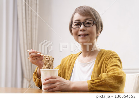 ダイニングでインスタント麺を食べるシニア女性 ダイニングでインスタント麺を食べるシニア女性 130354555