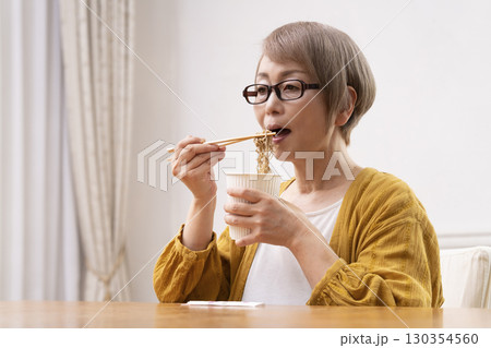ダイニングでインスタント麺を食べるシニア女性 ダイニングでインスタント麺を食べるシニア女性 130354560